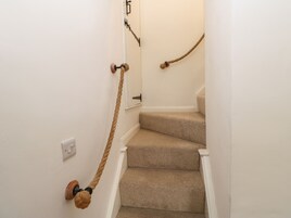 A carpeted staircase with a rope toy hanging from the wall.