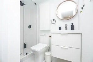 Et moderne badeværelse med toilet, vask og spejl.