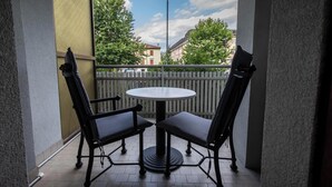 A balcony with two chairs and a table, a white fence, and buildings in the background. - Italianway - Bersaglio 25 - Ud-l483-bers25a1 (Udine)