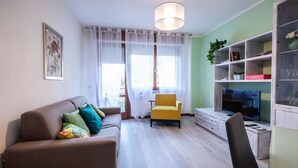 A living room with a sofa, armchair, TV, and shelves with books and decorative items. - Italianway - Bersaglio 25 - Ud-l483-bers25a1 (Udine)