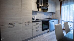 A modern kitchen with built-in appliances, a dining area with a glass table, and a view of the outdoors.