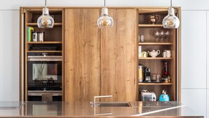 A modern kitchen with wooden cabinetry, a stainless steel countertop, and hanging pendant lights. - Exceptional Renovated Period Home in Clifton (Bristol)