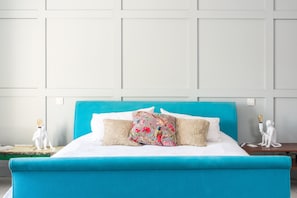 A bed with a teal headboard, white bedding, and floral-patterned pillows. - Exceptional Renovated Period Home in Clifton (Bristol)