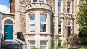 A multi-story building with a stone facade, a curved bay window, and a blue door. - Exceptional Renovated Period Home in Clifton (Bristol)