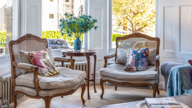 A room with two upholstered chairs, a small round table, and a vase with blue flowers. - Exceptional Renovated Period Home in Clifton (Bristol)