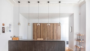 A modern kitchen with a central island, pendant lights, and wooden cabinetry. - Exceptional Renovated Period Home in Clifton (Bristol)