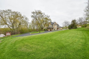 A large, two-story house with a well-maintained lawn and a driveway leading to the entrance.