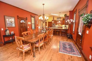 A dining area with a wooden table and chairs, a chandelier, and a rug.