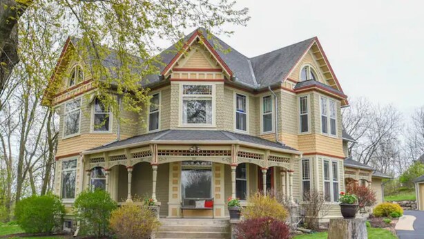 A large, two-story house with a prominent front porch, multiple windows, and a symmetrical design. - Beautifully Restored Historic Victorian (Waukesha)