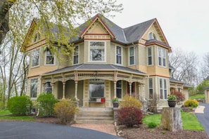 A large, two-story house with a prominent front porch, multiple windows, and a symmetrical design.