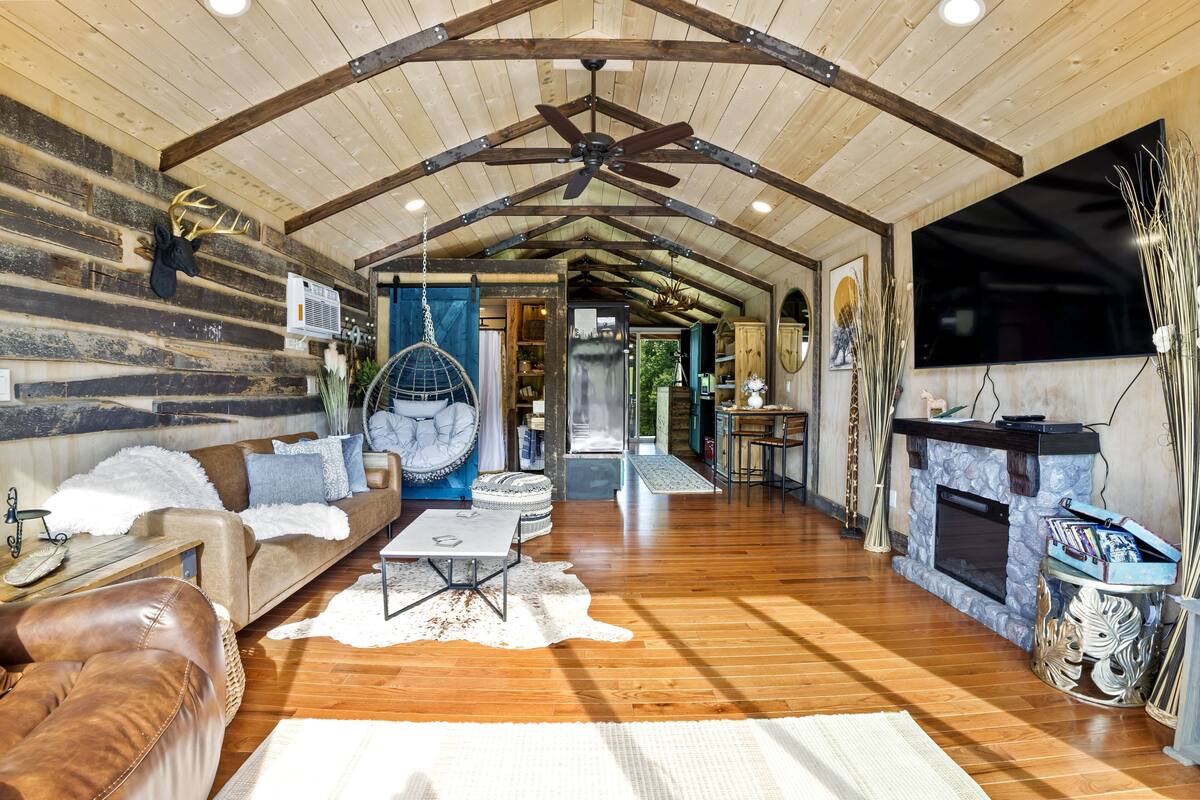A spacious living room with a wooden ceiling, a fireplace, and a television.