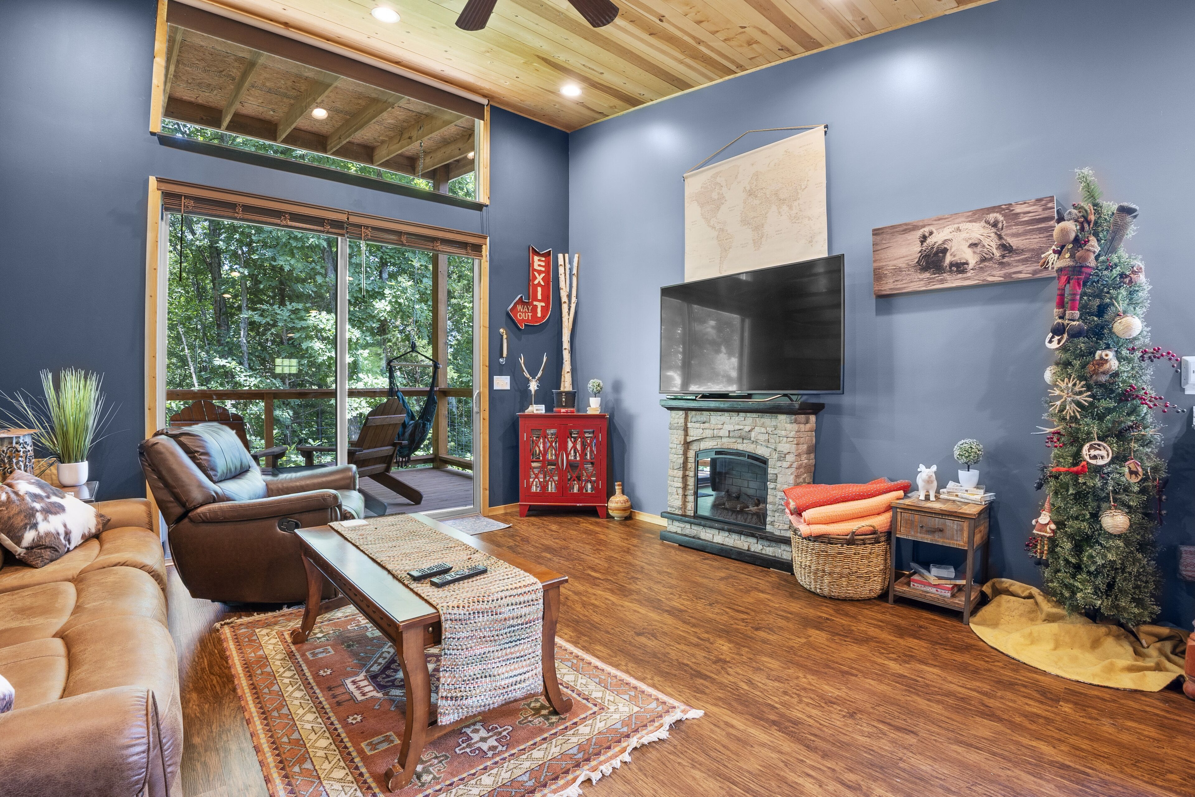 A cozy living room with a fireplace, leather furniture, and a Christmas tree.