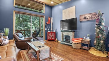A cozy living room with a fireplace, leather furniture, and a Christmas tree.