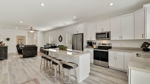 A modern kitchen with white cabinets, stainless steel appliances, and a central island with bar stools. - Watching Wildlife: Private Oasis for 4 w/ Patio, BBQ & Parking. Step Inside! (Payson)