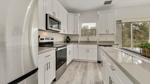 A modern kitchen with white cabinetry, stainless steel appliances, and a large window providing natural light. - Watching Wildlife: Private Oasis for 4 w/ Patio, BBQ & Parking. Step Inside! (Payson)