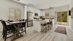 A modern kitchen with white cabinets, stainless steel appliances, and a central island with bar stools. - Watching Wildlife: Private Oasis for 4 w/ Patio, BBQ & Parking. Step Inside! (Payson)
