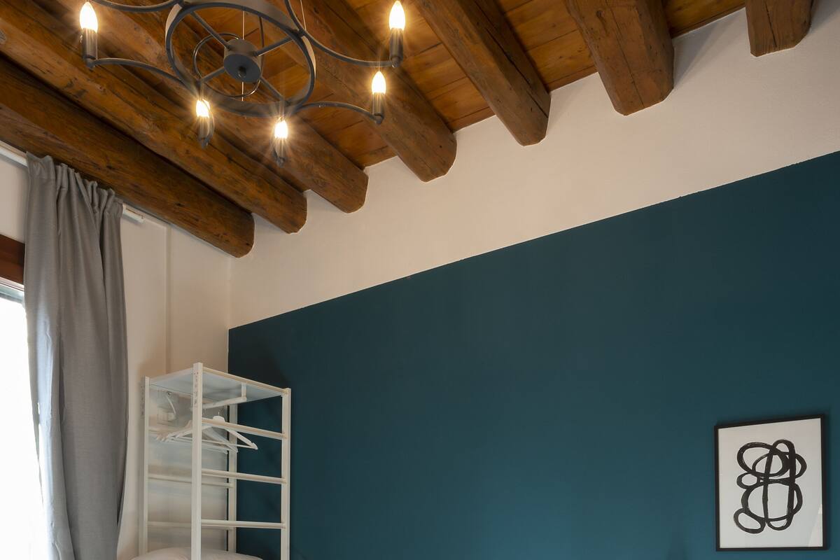 A bedroom with a bunk bed, a bedside table, a lamp, and a wall-mounted artwork.