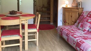 Un salon chaleureux avec une table et des chaises en bois, un canapé à motifs et un petit meuble.