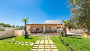 A modern house with a covered patio, a stone pathway, and a well-maintained lawn.