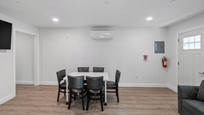 A dining area with a round table and six chairs, a fire extinguisher, and a door with a window. - Sea La Vie Ocean City, steps away from the Beach & Boardwalk (Ocean City)