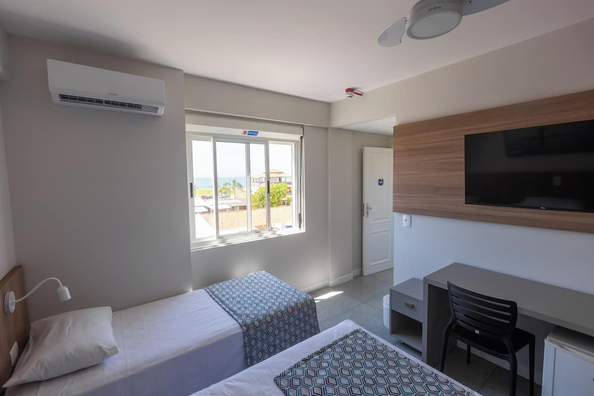 A hotel room with a bed, a desk, a chair, a TV, and a window with a view.