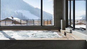 A spa area with a hot tub, large windows, and a view of snow-covered mountains. - Wifi, fitness, swimming pool, sauna, hammam, balcony, tv, ski locker, 75m², Le Grand Bornand (Le Grand-Bornand)