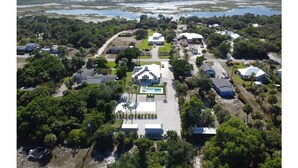 An aerial view of a residential area with houses, a swimming pool, and a large body of water in the background. - Containing Luxury in Jensen Beach-Sandollar (Jensen Beach)