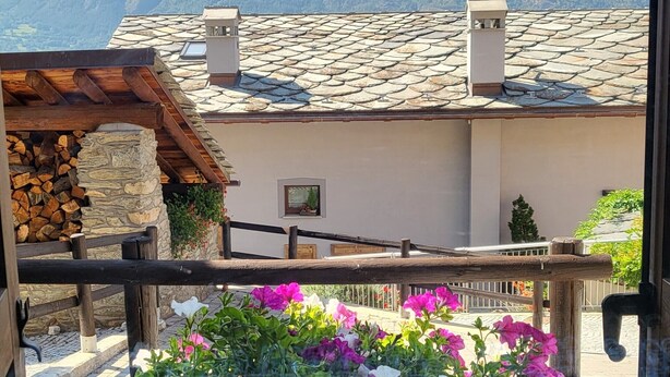 A balcony with a view of mountains, a stone wall, and a wooden fence. - Luciana house (Saint Christophe)