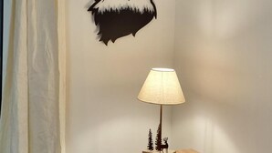 Une pièce comprenant une commode en bois, une lampe, un petit tabouret et une décoration murale représentant un loup.