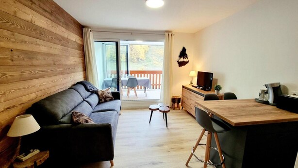 Un salon moderne comprenant un canapé, une table basse, un téléviseur et un coin repas avec une table et des chaises en bois.