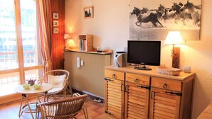 A cozy room with a wooden cabinet, a television, a wicker chair, and a table with bowls. - 100m from ski slopes, 5th floor, tv, 30m², Vars (Vars)