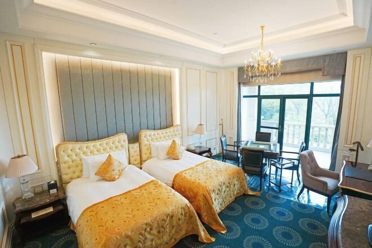Ein Hotelzimmer mit zwei Betten, einem Schreibtisch, einem Stuhl und einem großen Fenster.