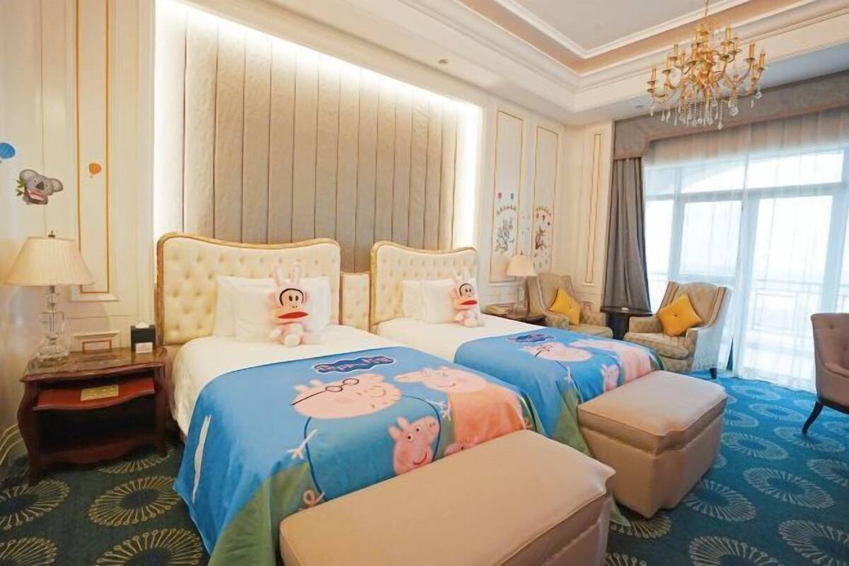 Ein Hotelzimmer mit zwei Betten, einer Kristallleuchter, einem großen Fenster und einem gemusterten Teppich.