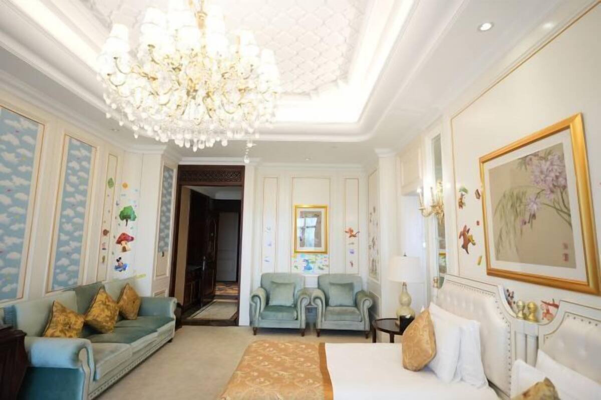 Ein luxuriöses Schlafzimmer mit einem großen Bett, einer Chandelier, einer Couch und einem Sessel.