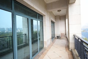 A balcony with glass doors, a tiled floor, and a view of buildings. - Hubei Culture and Tourism Honglian Lake Hotel (Ezhou)