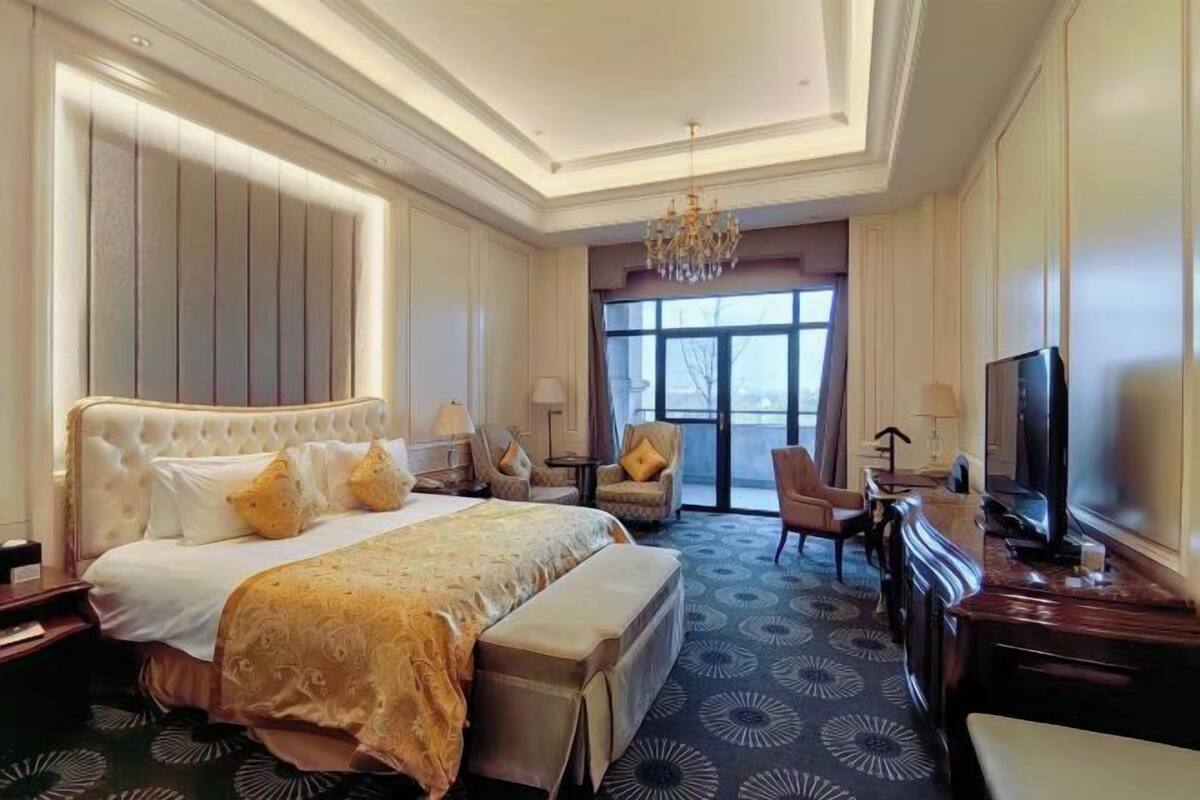 Ein Hotelzimmer mit einem großen Bett, einem Fernseher, einem Schreibtisch und einem Sessel.
