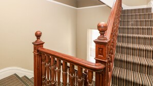 A wooden staircase with a handrail and balusters, leading to a landing with a door. - Sunshine Apartment (Belper)