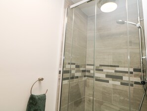 A glass-enclosed shower with a handheld showerhead and a handheld shower attachment. - Sunshine Apartment (Belper)