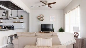 Ein modernes Wohnzimmer mit einer Couch, einem Fernseher und einem Deckenventilator.