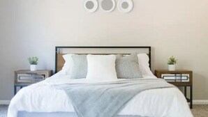 Ein Schlafzimmer mit einem Bett, zwei Nachttischen und einer Wandleuchte.