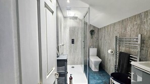 A modern bathroom with a shower, toilet, and sink.