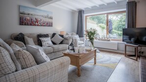A cozy living room with a sofa, coffee table, and a TV. - Wern Y Glais - 2 Bedroom Cottage - Glais (Swansea)