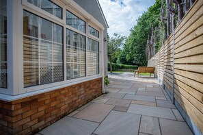 A brick house with large windows, a paved patio, and a wooden fence.