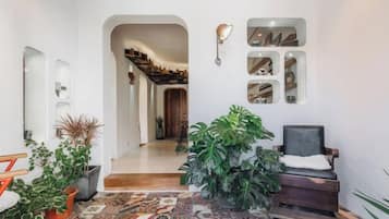Un corridoio con pavimento decorato, una zona relax con una poltrona e una scala che conduce a un altro piano.
