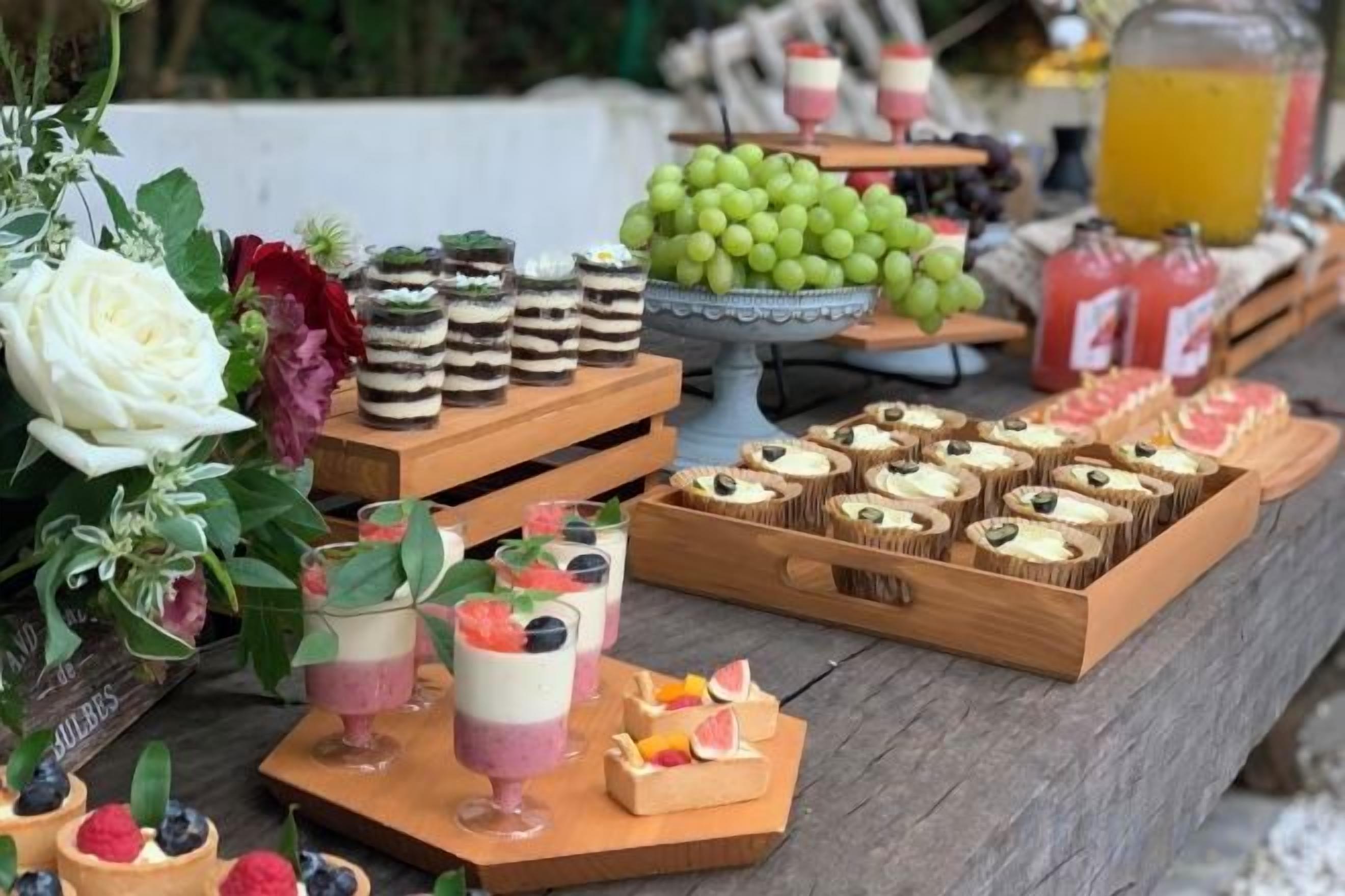 A table with various food items including desserts, fruits, and beverages.