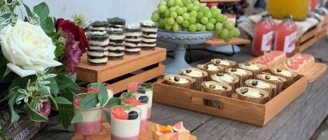 A table with various food items including desserts, fruits, and beverages.