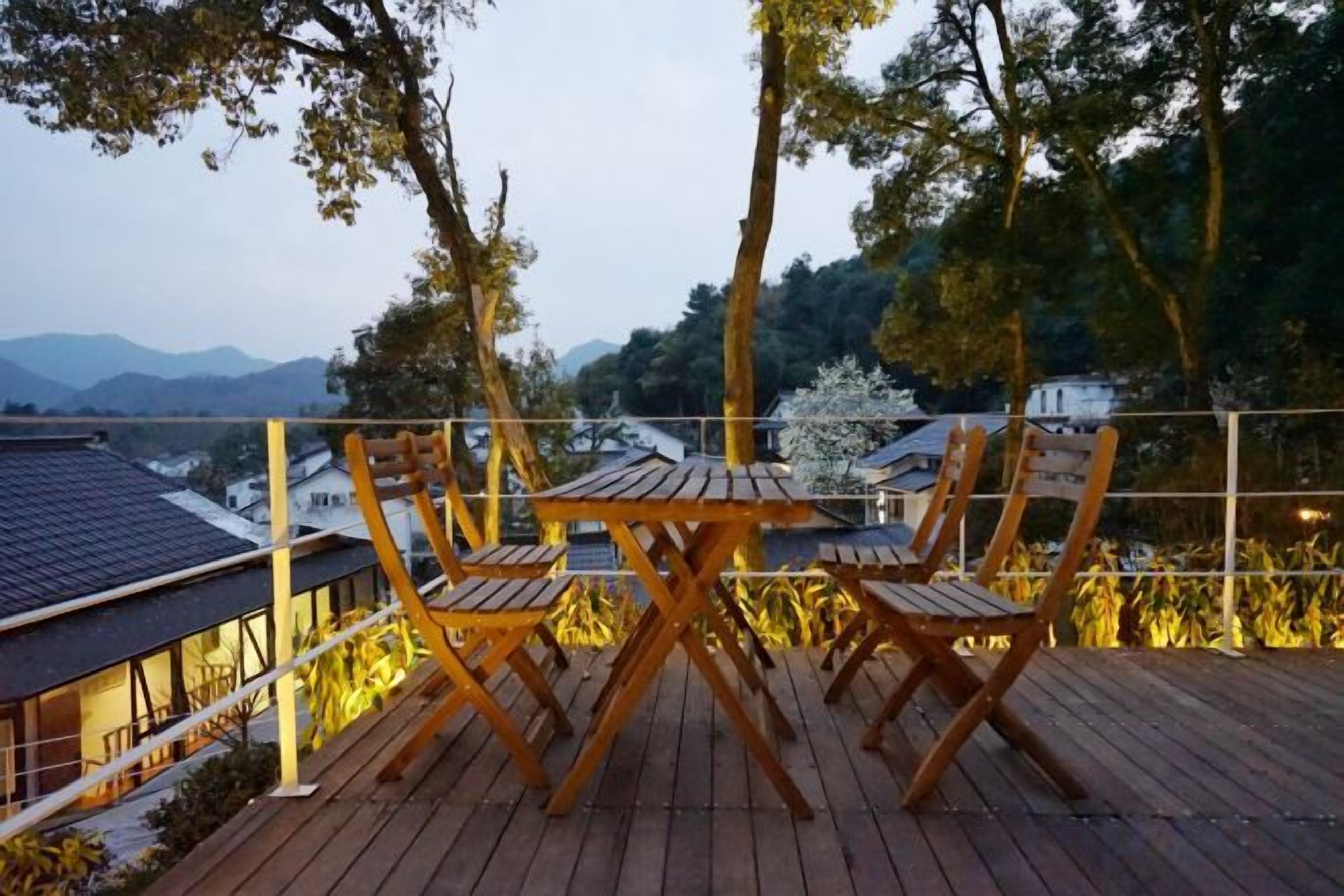 A wooden deck with a table and chairs, overlooking a mountainous landscape.
