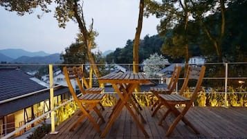 Una terraza de madera con mesa y sillas, con vistas a un paisaje montañoso.