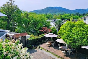 A patio area with outdoor furniture, a view of a village, and a mountain in the background.