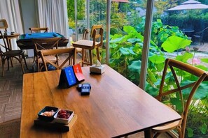 Una mesa de madera con sillas, un menú azul, una caja pequeña y un cuenco con fruta.